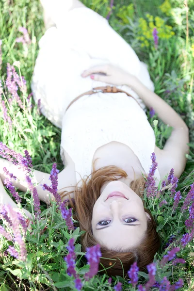 Junges Modemädchen legt sich ins grüne Gras. — Stockfoto