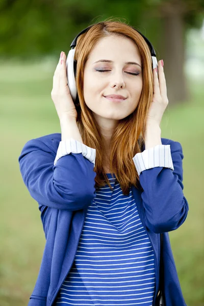 Menina de moda jovem com fones de ouvido na primavera ao ar livre . — Fotografia de Stock