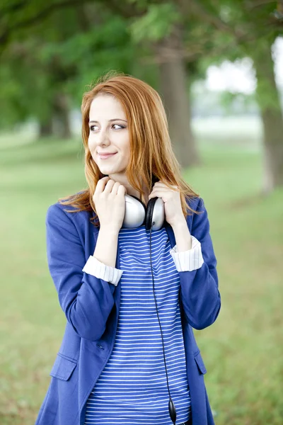 Ung flicka med hörlurar på våren utomhus. — Stockfoto