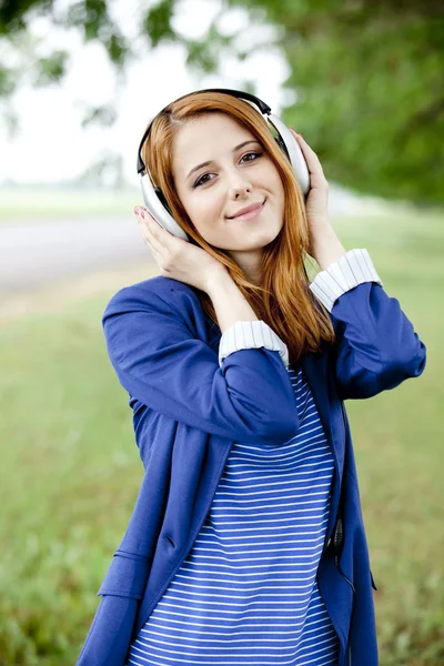 Jonge mode meisje met koptelefoon op lente buiten. — Stockfoto