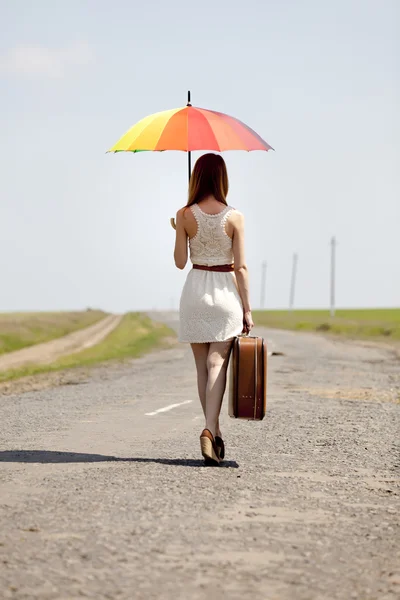 Jonge mode meisje met paraplu en koffer in voorjaar buiten. — Stockfoto