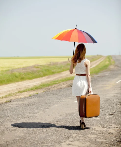 Молодая девушка моды с зонтиком и чемоданом на весеннем открытом воздухе . — стоковое фото