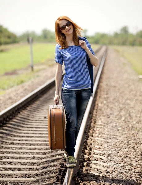 Young fashion girl with suitcase at railways. Stock Photo