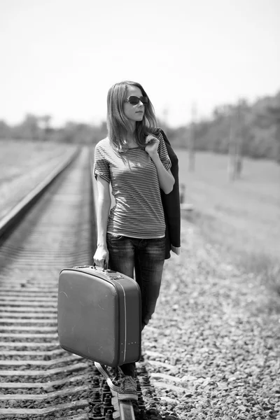 Young fashion girl with suitcase at railways. Royalty Free Stock Images