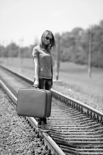 Young fashion girl with suitcase at railways. Stock Photo