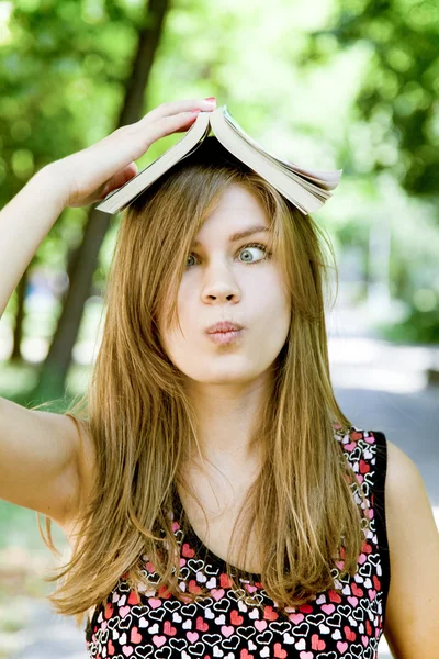 Meisje met boek over hoofd. — Stockfoto