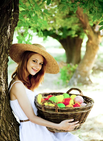 Красивая рыжая девушка с фруктами в корзине в саду . — стоковое фото