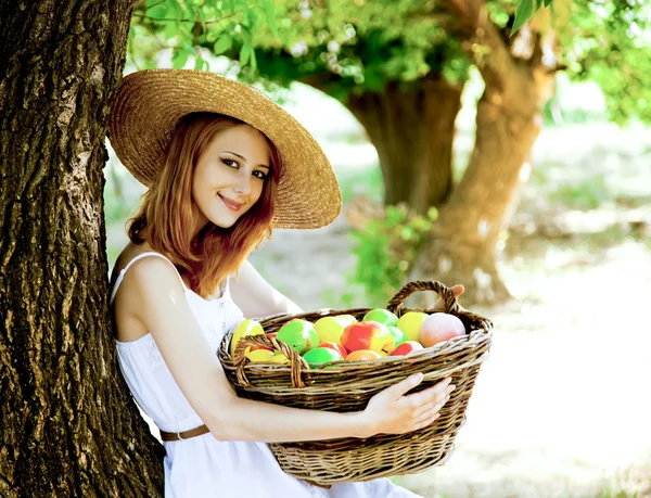 Красива руда дівчина з фруктами в кошику в саду . — стокове фото