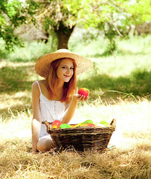 Beautiful redhead girl with fruits in basket at garden. Royalty Free Stock Photos