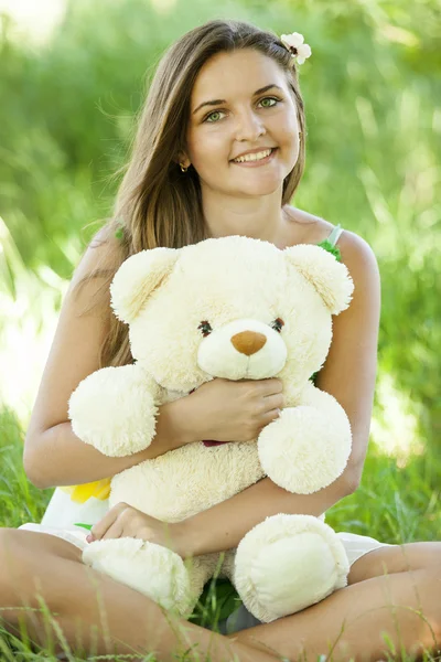 Menina adolescente bonita com ursinho de pelúcia no parque em grama verde . — Fotografia de Stock