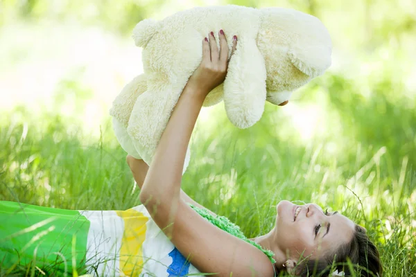 Όμορφο κορίτσι, με αρκουδάκι στο πάρκο στο πράσινο γρασίδι. — Φωτογραφία Αρχείου
