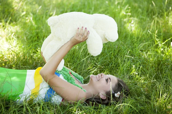 Oyuncak ayı parkta yeşil çimen, güzel genç kızla. — Stok fotoğraf