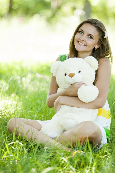 Piękna dziewczyna z misiem w parku na zielonej trawie. — Zdjęcie stockowe