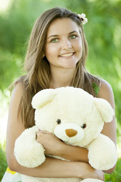 Krásná dospívající dívka s Medvídek v parku na zelené trávě. — Stock fotografie