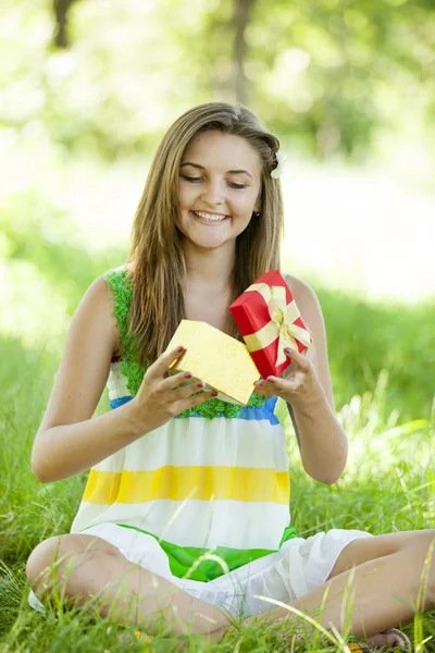Schöne Teenie-Mädchen mit Geschenk im Park auf grünem Gras. — Stockfoto