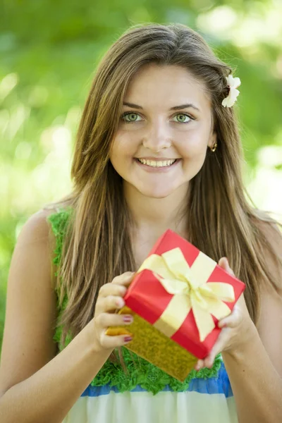 Szép tini lány a parkban, a zöld fű ajándék. — Stock Fotó