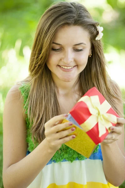 Bella ragazza adolescente con regalo nel parco a erba verde . — Foto Stock