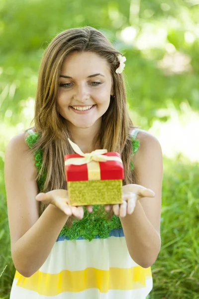 Hermosa chica adolescente con regalo en el parque en la hierba verde . —  Fotos de Stock