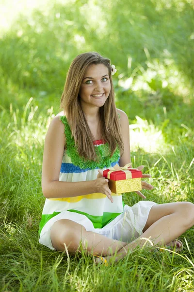 Piękna dziewczyna z pamiątkami w parku na zielonej trawie. — Zdjęcie stockowe