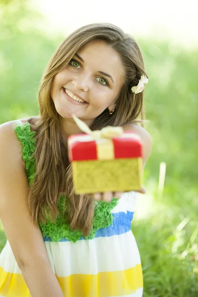 Hermosa chica adolescente con regalo en el parque en la hierba verde . — Foto de Stock