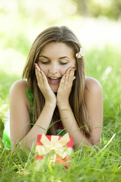 Überrascht schöne Teen-Mädchen mit Geschenk im Park an der grünen Gra — Stockfoto