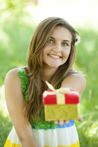 Красива дівчина-підліток з подарунком в парку на зеленій траві . — стокове фото