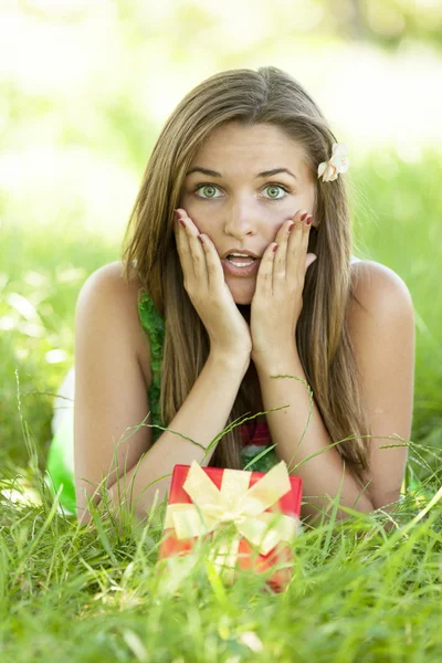 Surpreendido bela menina adolescente com presente no parque em verde gra — Fotografia de Stock