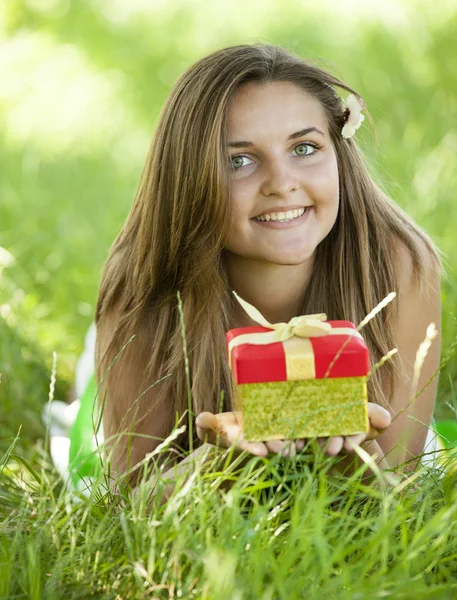Menina adolescente bonita com presente no parque na grama verde . — Fotografia de Stock