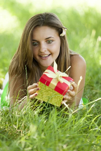 Menina adolescente bonita com presente no parque na grama verde . — Fotografia de Stock