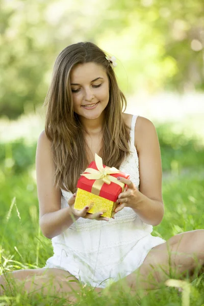 Gadis cantik dengan hadiah di taman di rumput hijau . — Stok Foto