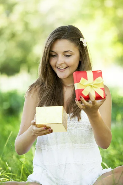 Beautiful teen girl with gift in the park at green grass. — Stock Photo, Image