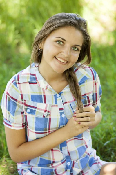 Krásná dospívající dívka v parku na zelené trávě. — Stock fotografie