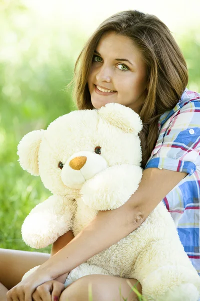 Όμορφο κορίτσι, με αρκουδάκι στο πάρκο στο πράσινο γρασίδι. — Φωτογραφία Αρχείου