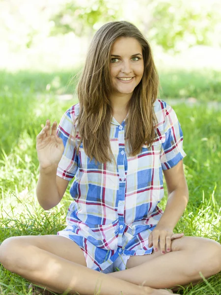 Mooie tiener meisje in het park op groen gras. — Stockfoto