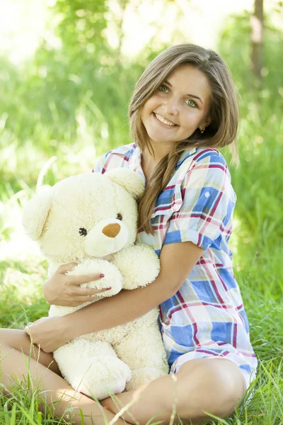 Bella ragazza adolescente con orsacchiotto nel parco a erba verde . — Foto Stock