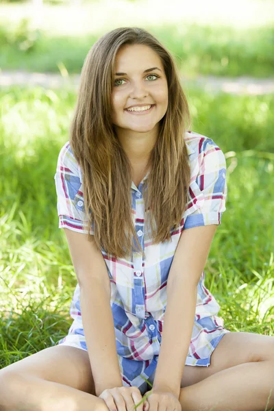 Szép tini lány a parkban, a zöld fű. — Stock Fotó