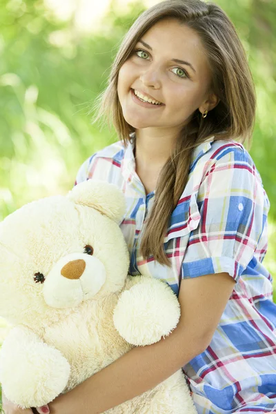 Krásná dospívající dívka s Medvídek v parku na zelené trávě. — Stock fotografie