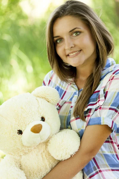 Hermosa chica adolescente con oso de peluche en el parque en la hierba verde . — Foto de Stock