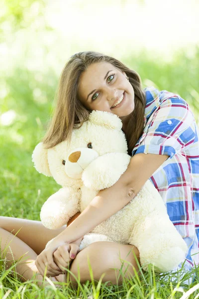 Hermosa chica adolescente con oso de peluche en el parque en la hierba verde . — Foto de Stock