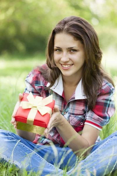 Hermosa chica adolescente con regalo en el parque en la hierba verde . —  Fotos de Stock