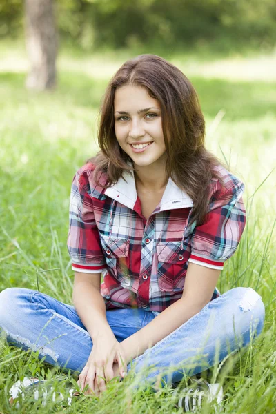 Mooie tiener meisje in het park op groen gras. — Stockfoto