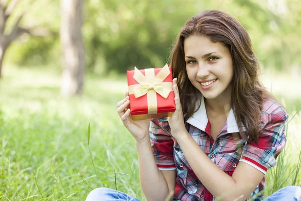 Bella ragazza adolescente con regalo nel parco a erba verde . — Foto Stock