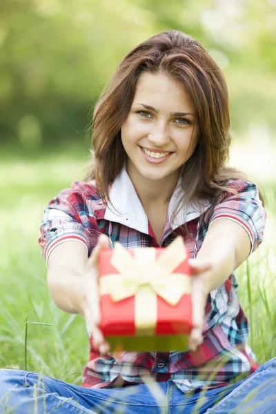 Schöne Teenie-Mädchen mit Geschenk im Park auf grünem Gras. — Stockfoto