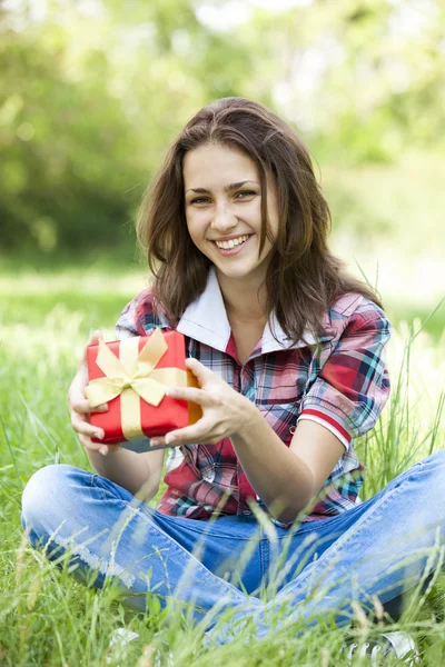 Hermosa chica adolescente con regalo en el parque en la hierba verde . — Foto de Stock