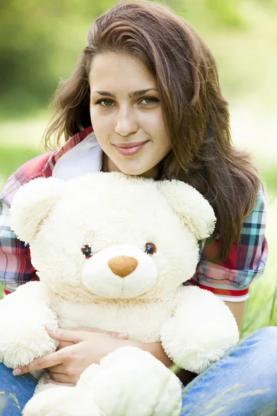 Schöne Teenie-Mädchen mit Teddybär im Park auf grünem Gras. — Stockfoto