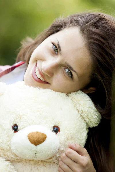 Красива підлітків дівчина з ведмедиком в парку, на зеленій траві. — стокове фото
