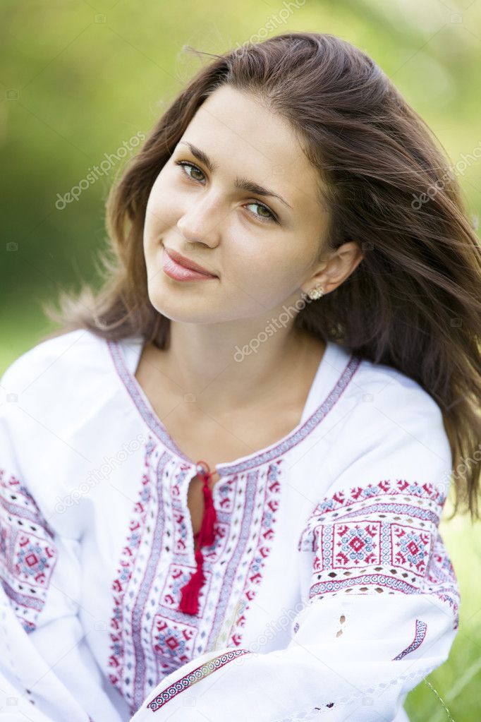 Slav teen girl at green meadow in national ukrainian clothing.