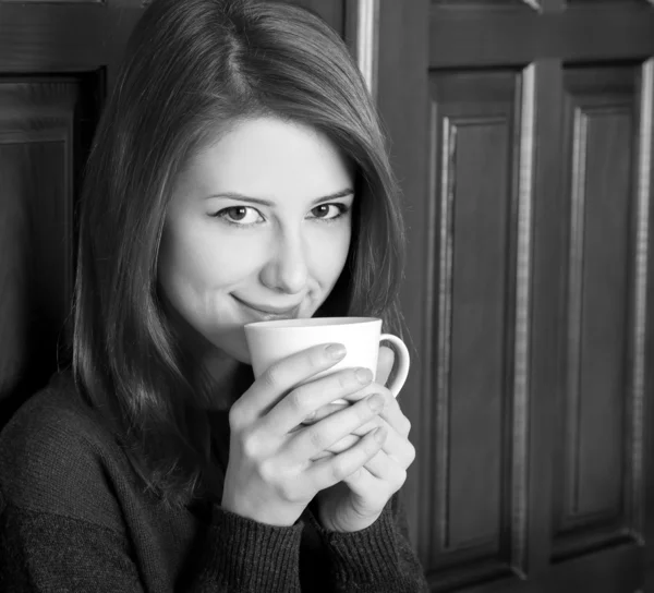 Style girl drinking coffee near wood doors. Photo in black and w — Stock Photo, Image