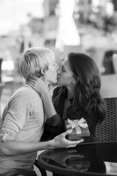 Młody mężczyzna daje prezent młodej dziewczynie w kawiarni. — Zdjęcie stockowe