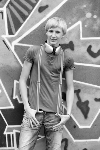 Style teen boy with headphones near graffiti background. — Stock Photo, Image